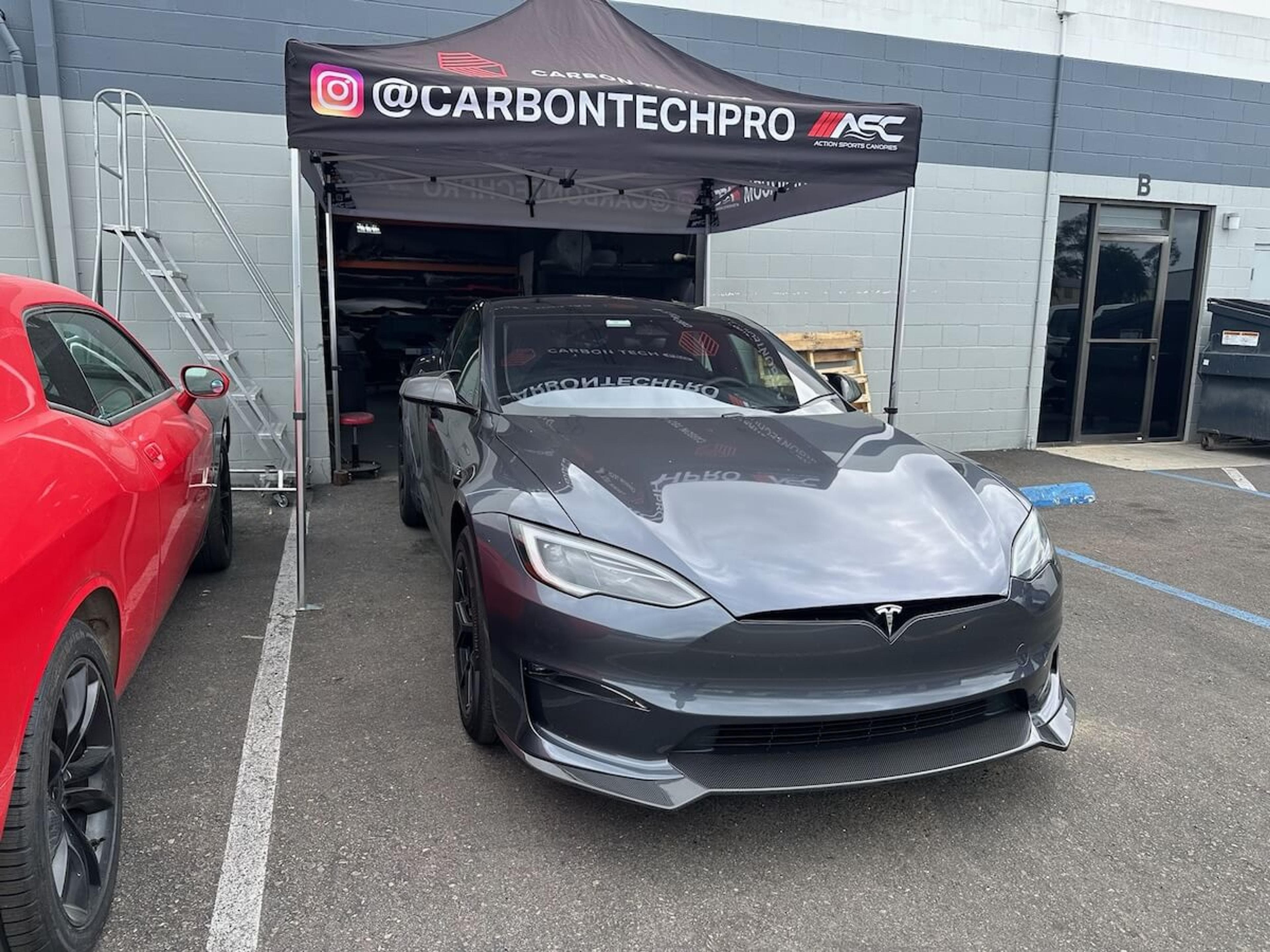 Gray Tesla Model Y with installed carbon fiber front lip outside Carbon Tech Pro