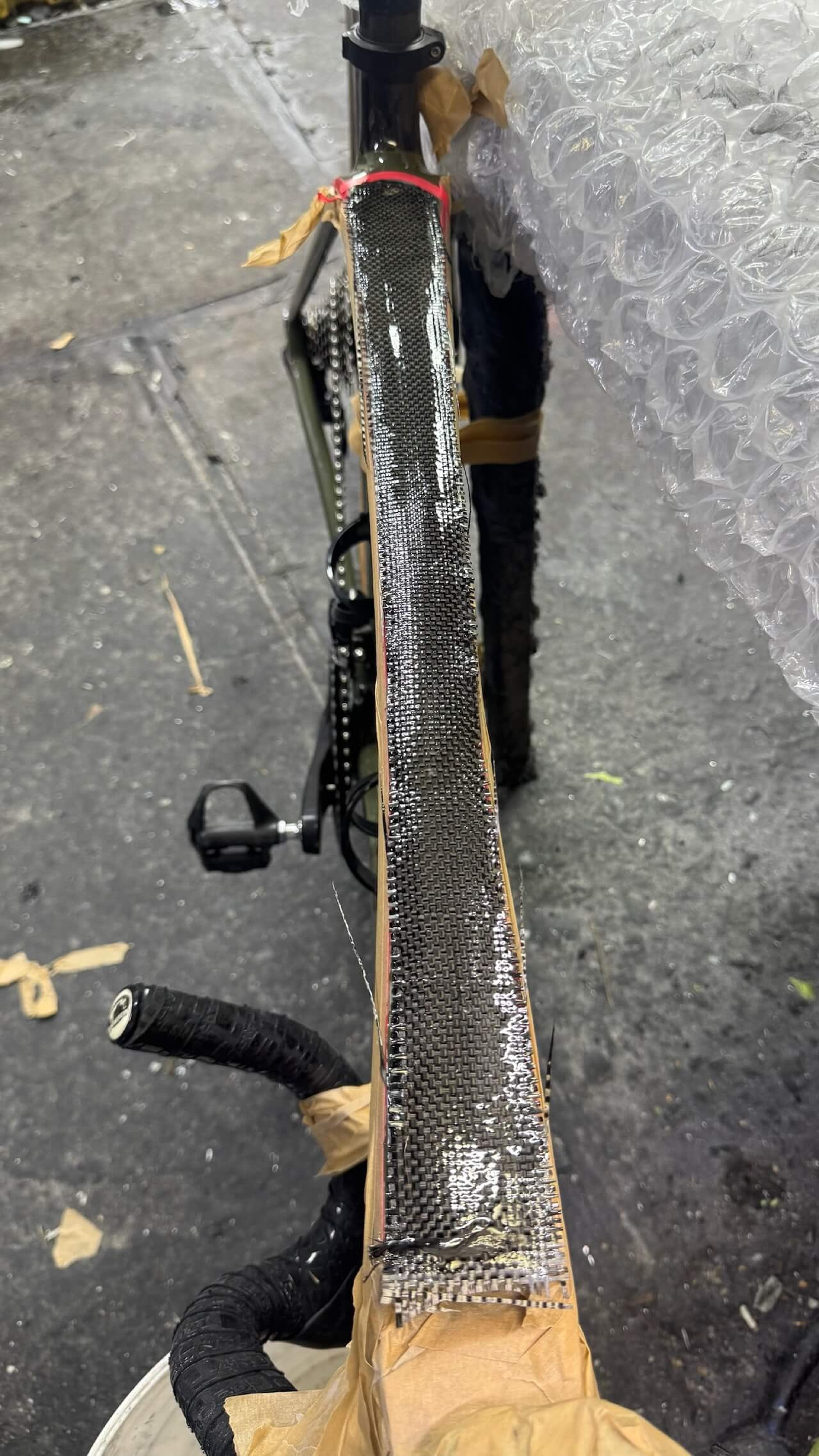 Close-up of carbon fiber reinforcement applied to the Trek Émonda SL top tube during frame repair