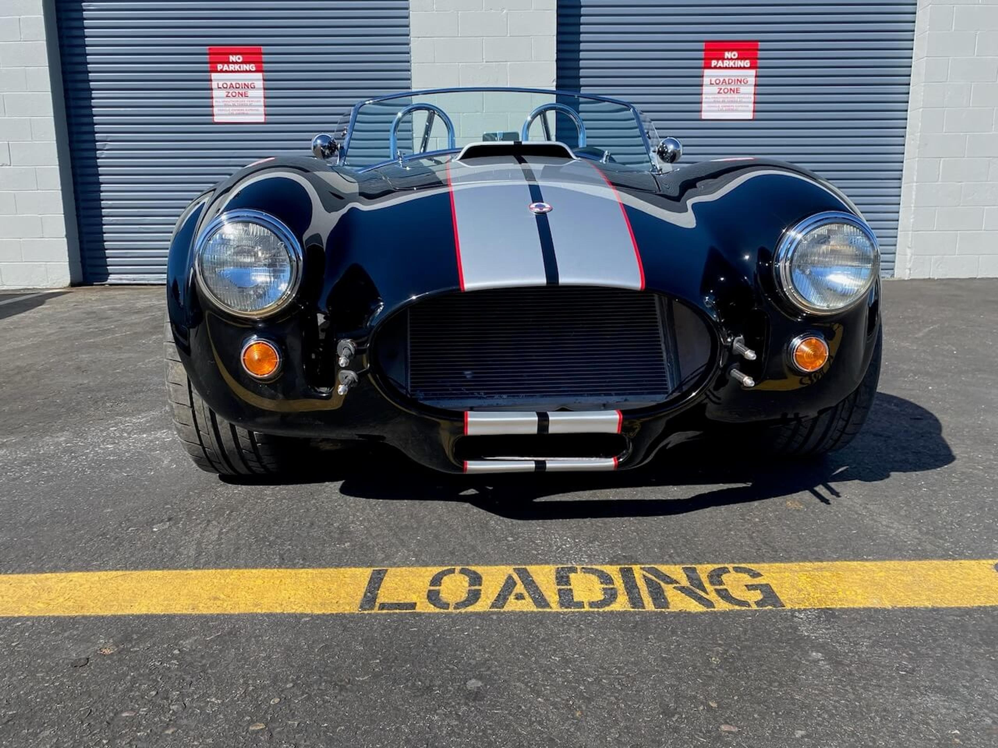Straight-on view of the completed black Shelby Cobra 427-style roadster after fiberglass repair