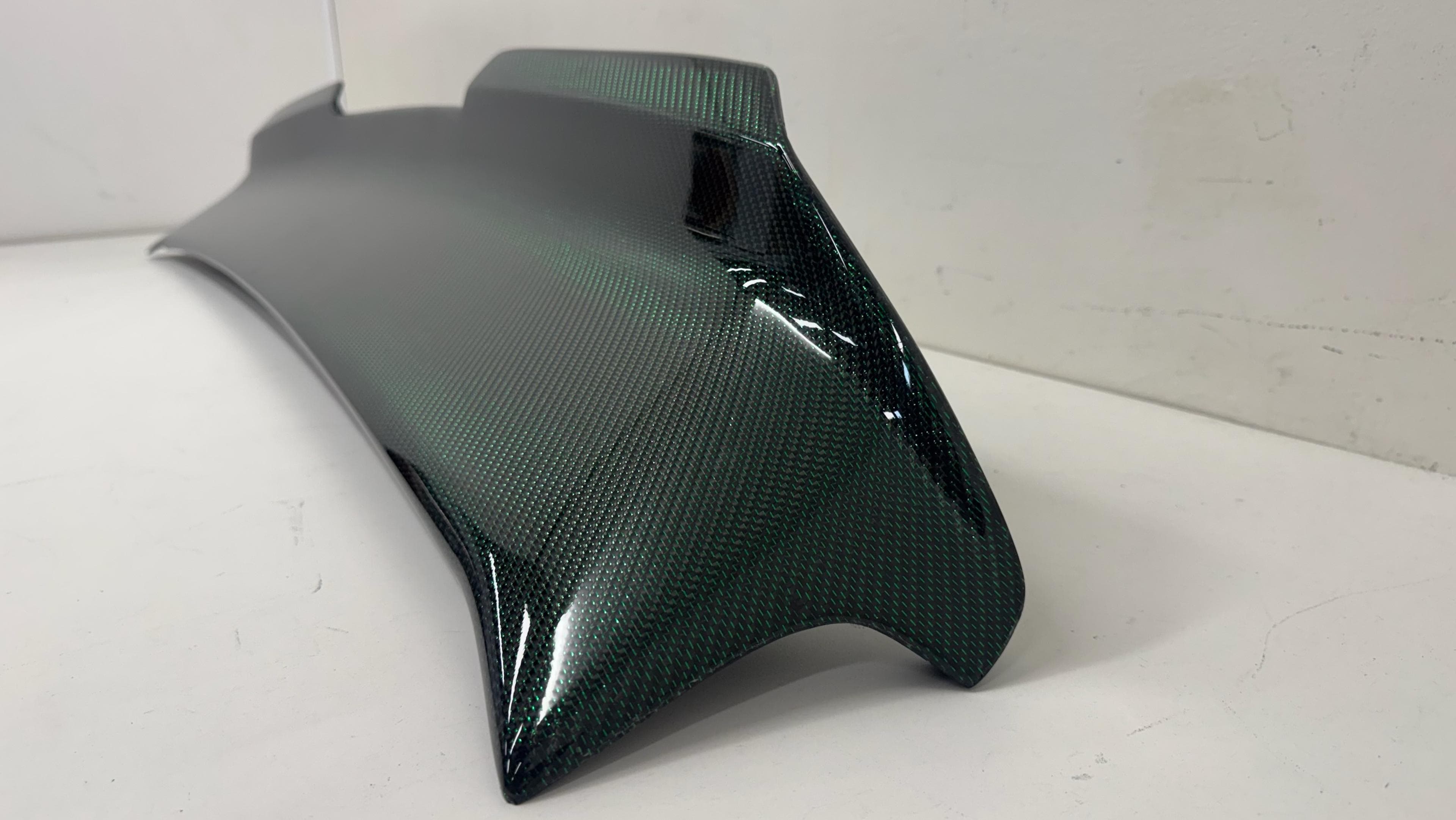 Close-up of green twill reflective carbon fiber spoiler weave finish.