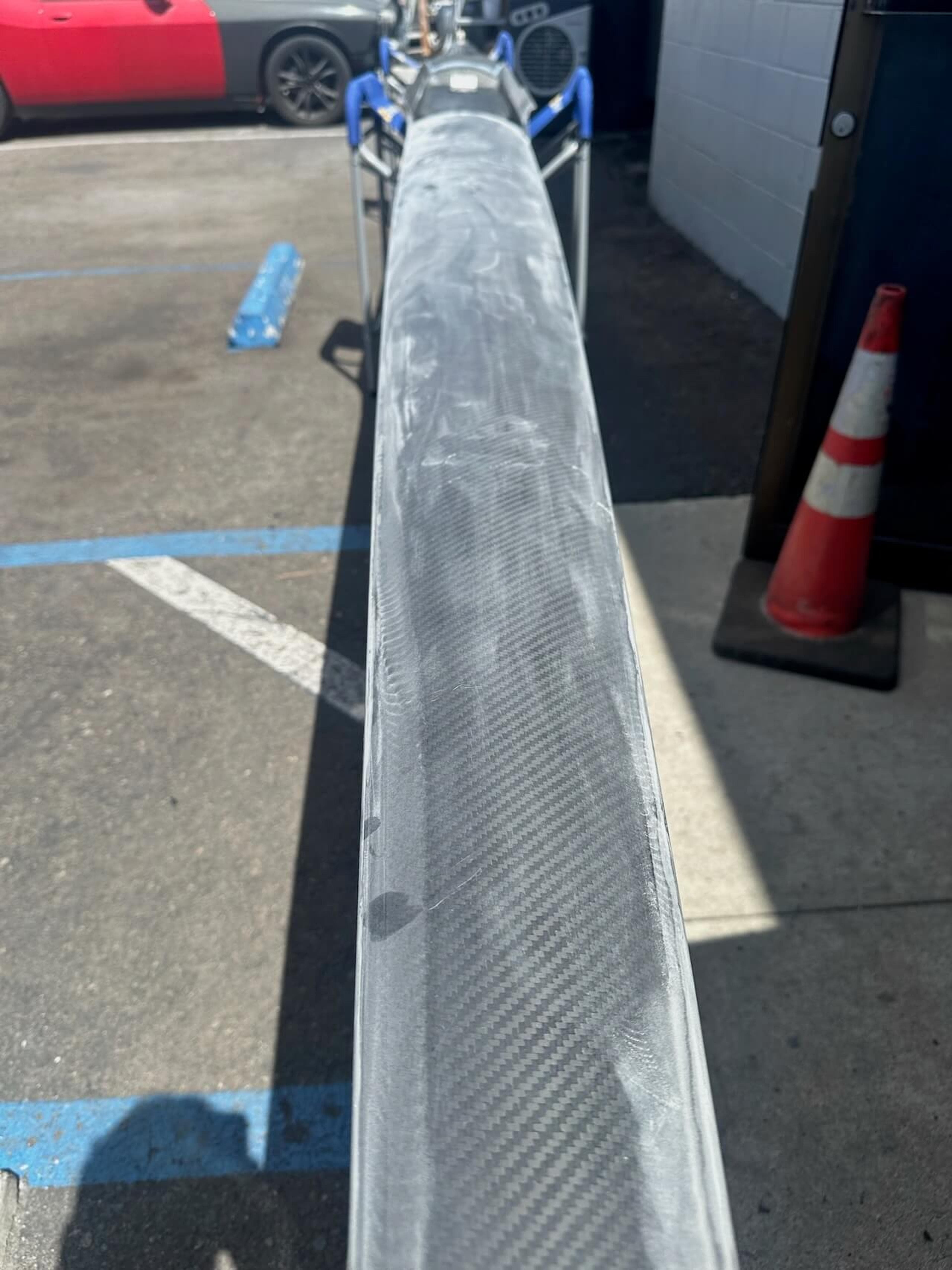 Sanded and damaged section of a Fluidesign carbon fiber rowing shell before repair
