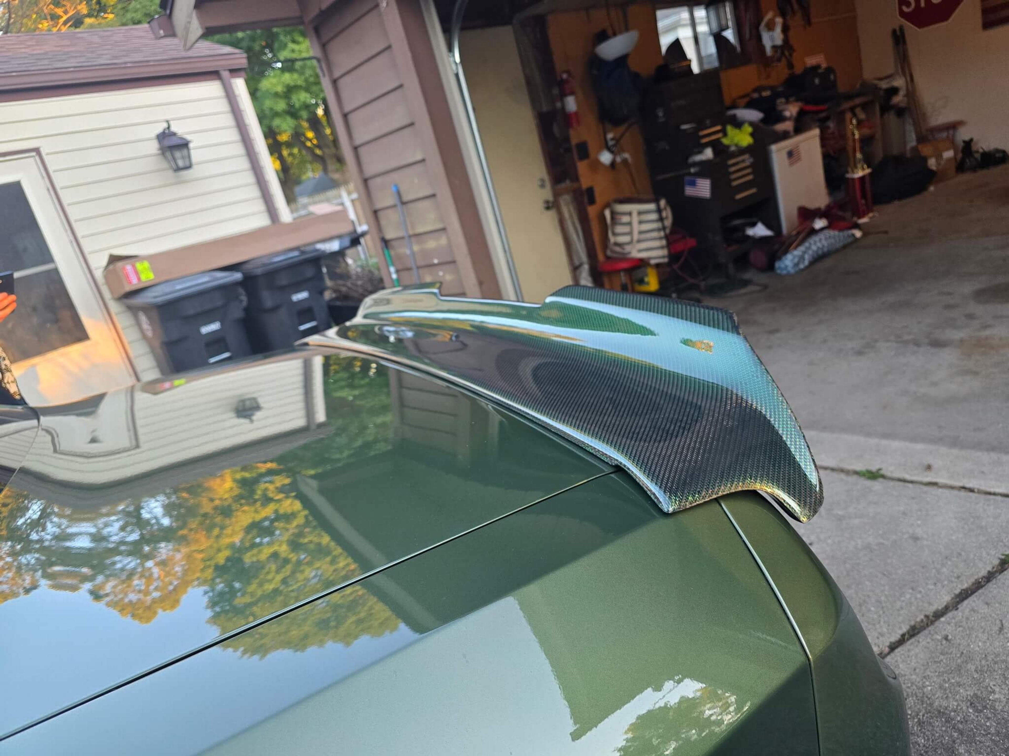 Close-up of a green reflective carbon fiber spoiler fitted to a Dodge Challenger trunk.