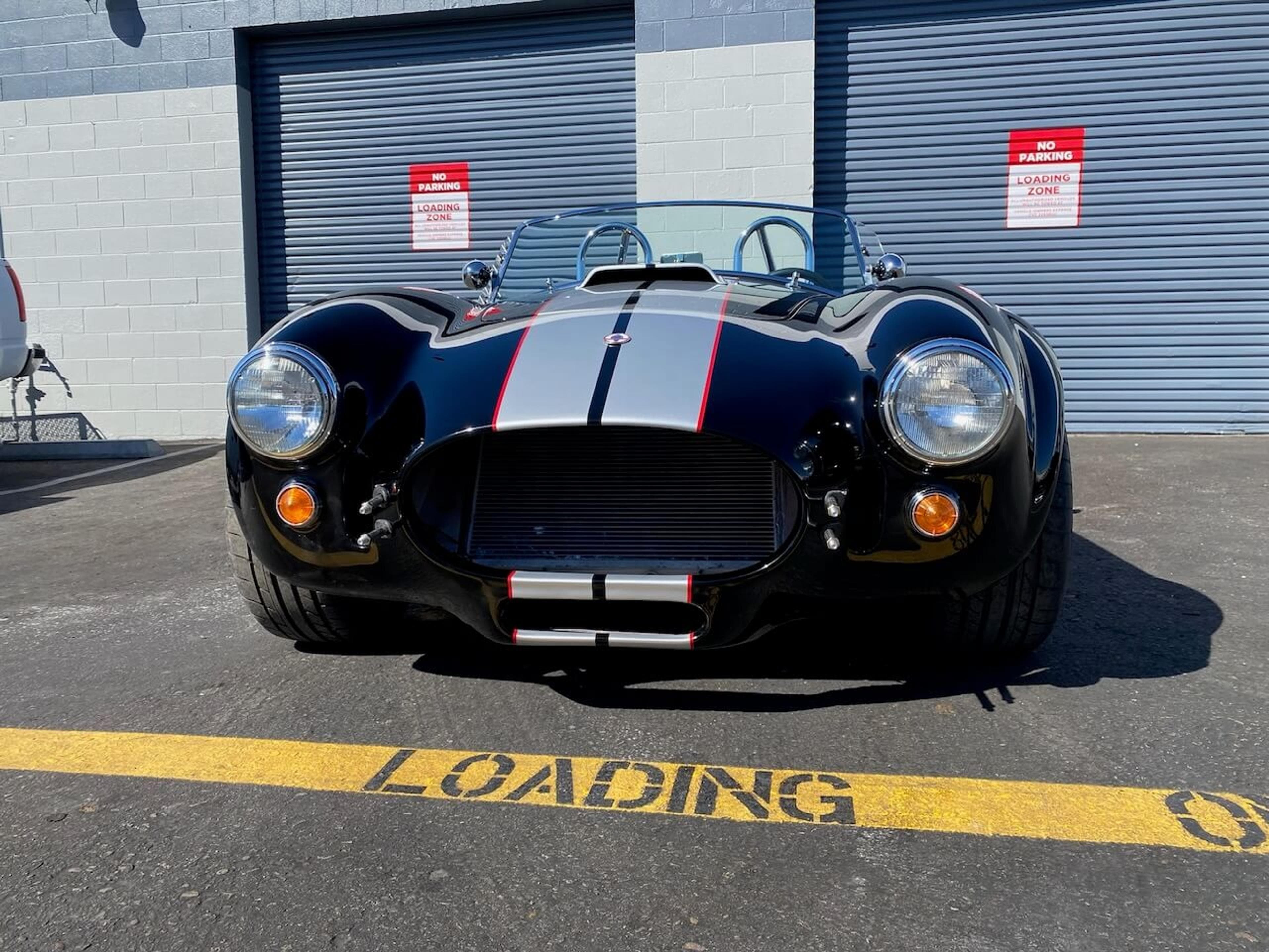 Full front view of the Shelby Cobra-style roadster showing the completed fiberglass body repair