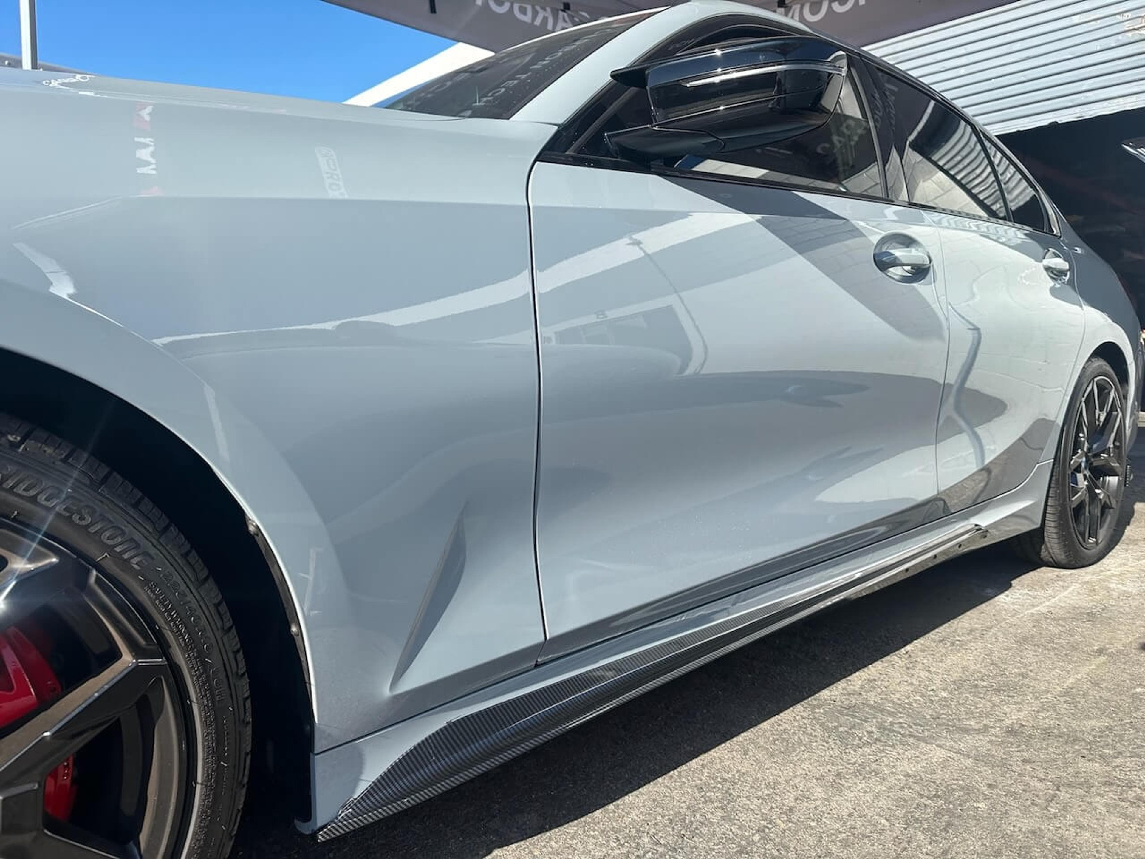 Side view of a 2026 BMW M340i showing the installed carbon fiber side skirts