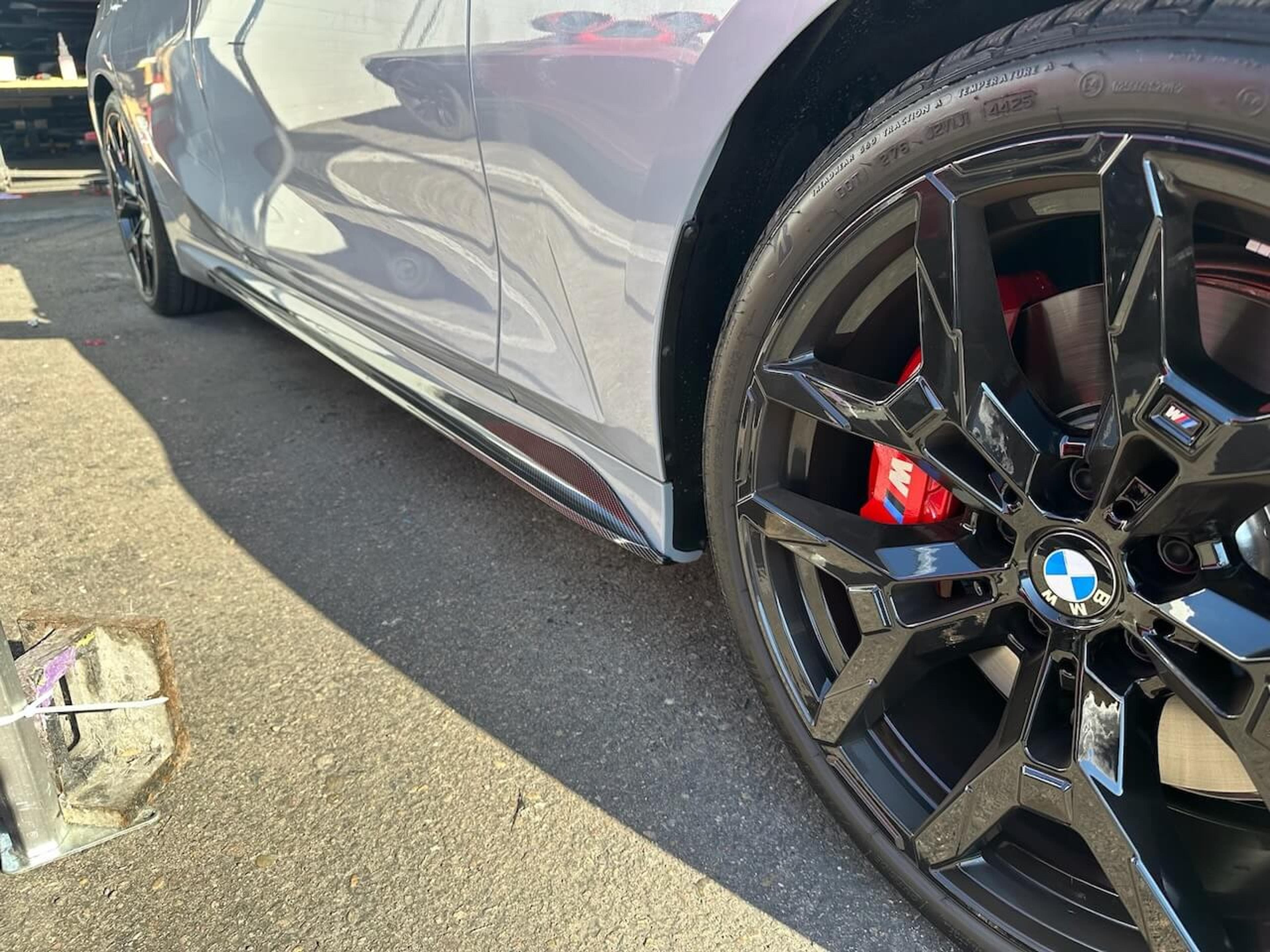 Rear view of a BMW M340i with the lower diffuser removed and installation components laid out below