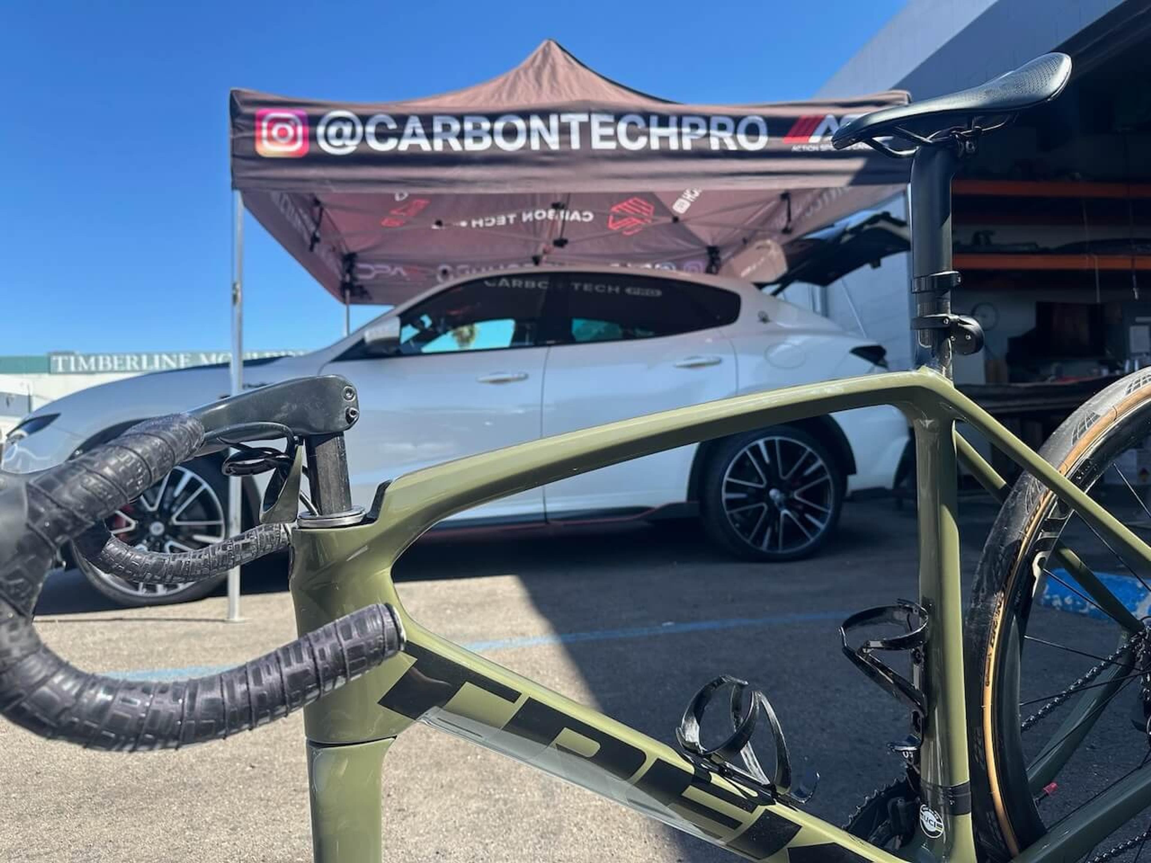 Finished Trek Émonda SL road bike displayed in front of the Carbon Tech Pro workshop banner