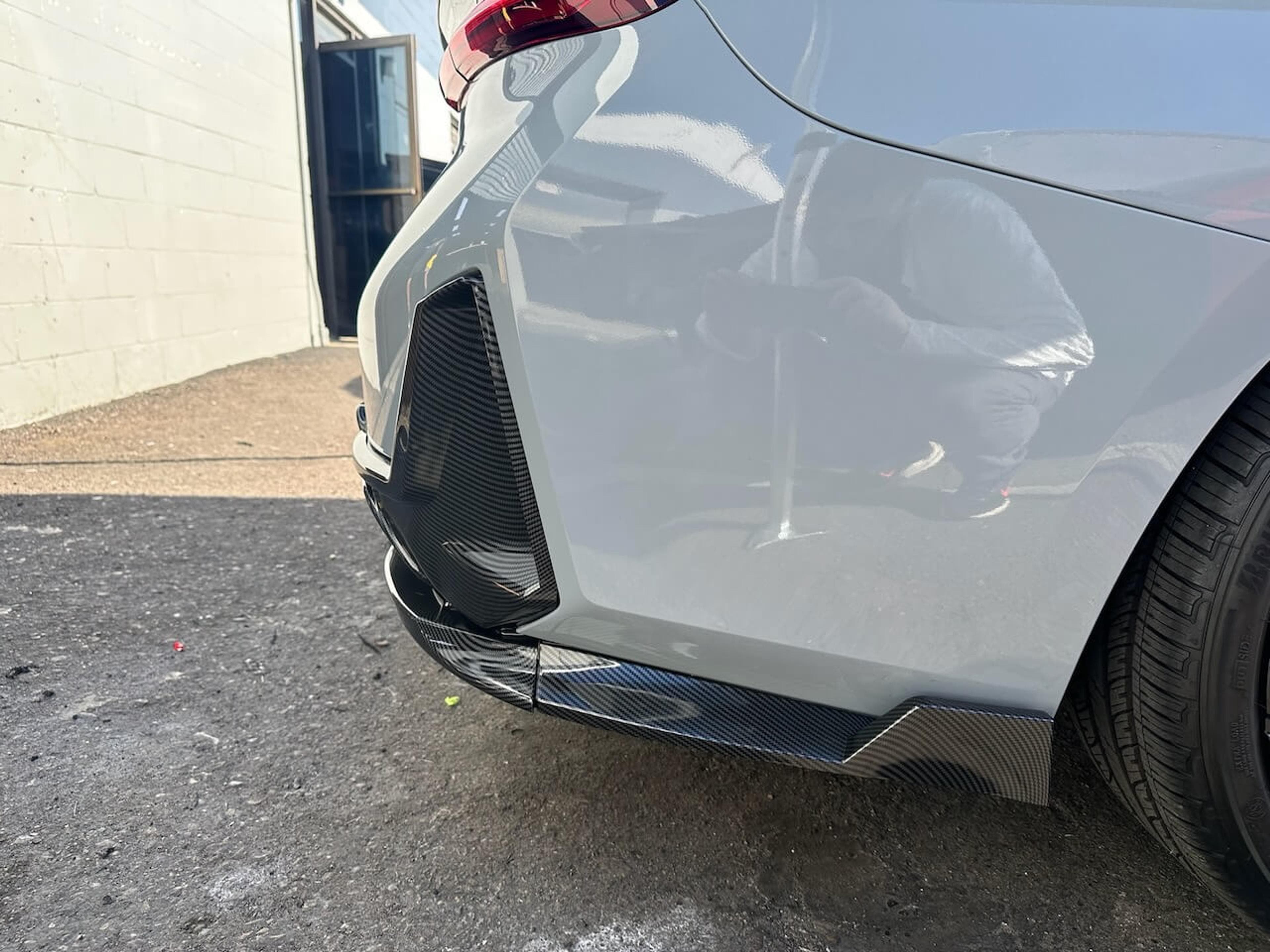 Close-up of a BMW M340i carbon fiber side skirt beside the front wheel