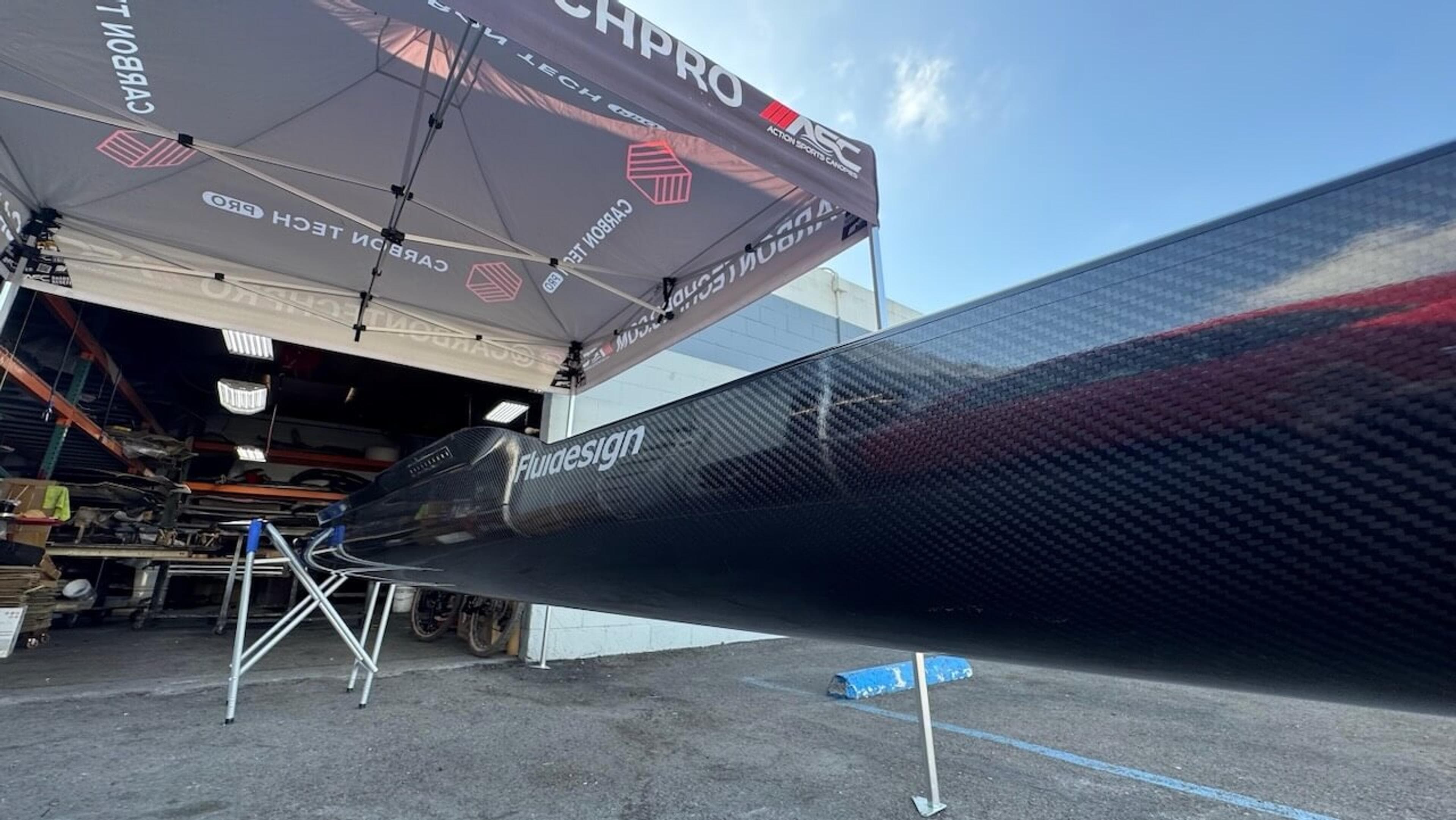 Close-up view of Fluidesign carbon fiber rowing shell showing the repaired glossy carbon fiber surface