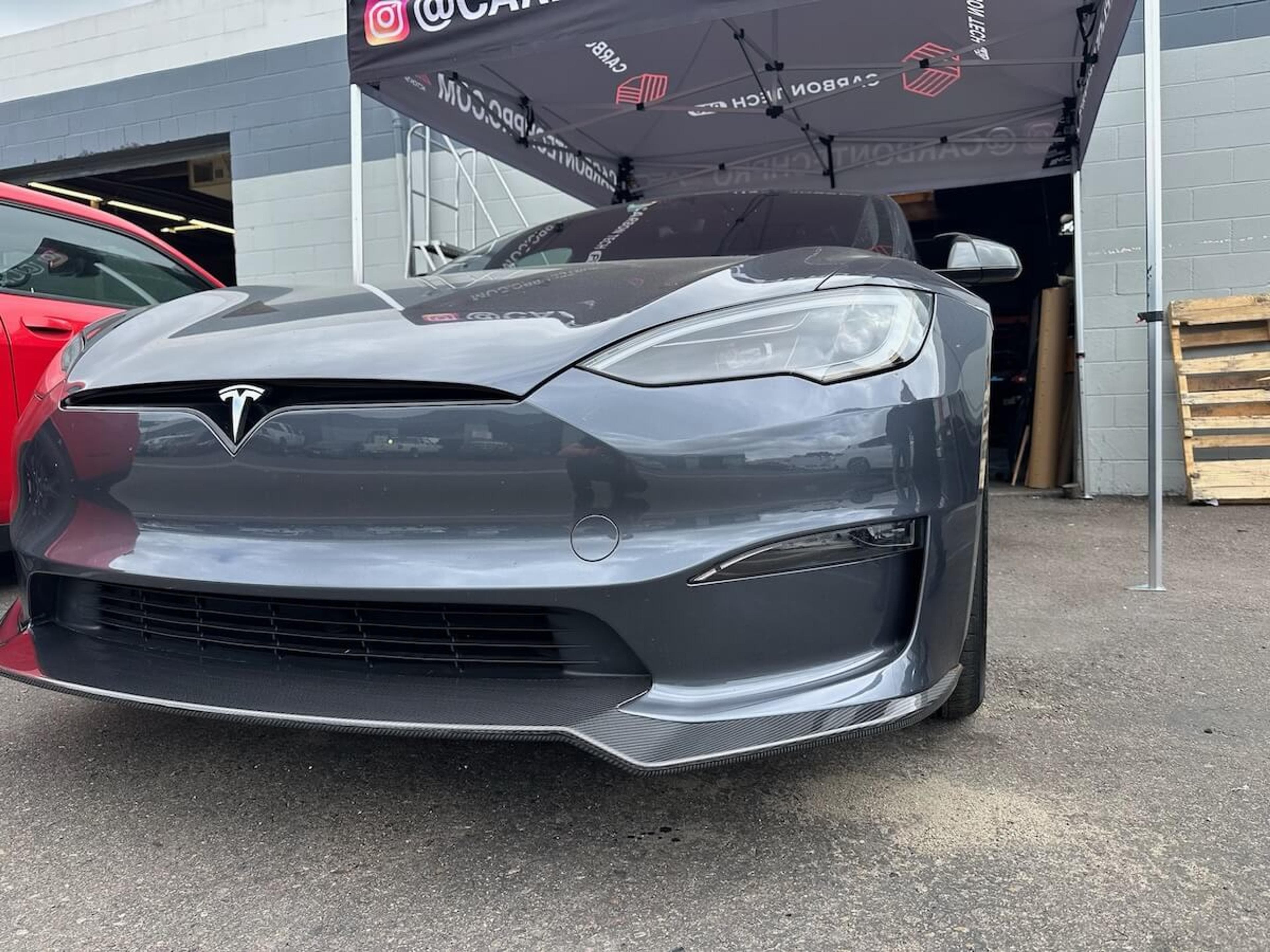 Close-up front view of gray Tesla Model Y with carbon fiber front lip installed