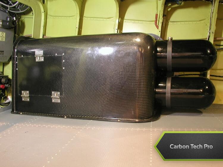 Carbon fiber interior housing and tank assembly engineered for lightweight durability. Custom carbon fiber box and dark dual tanks installed inside an aircraft cabin interior.